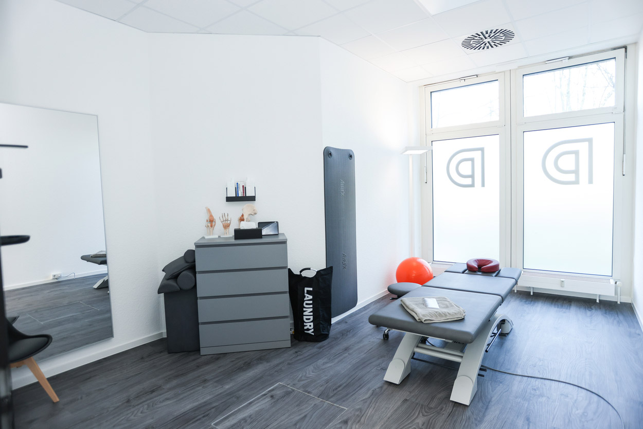Ein heller Physiotherapie-Raum mit Behandlungsliege und Fitnessgeräten, modern und minimalistisch.