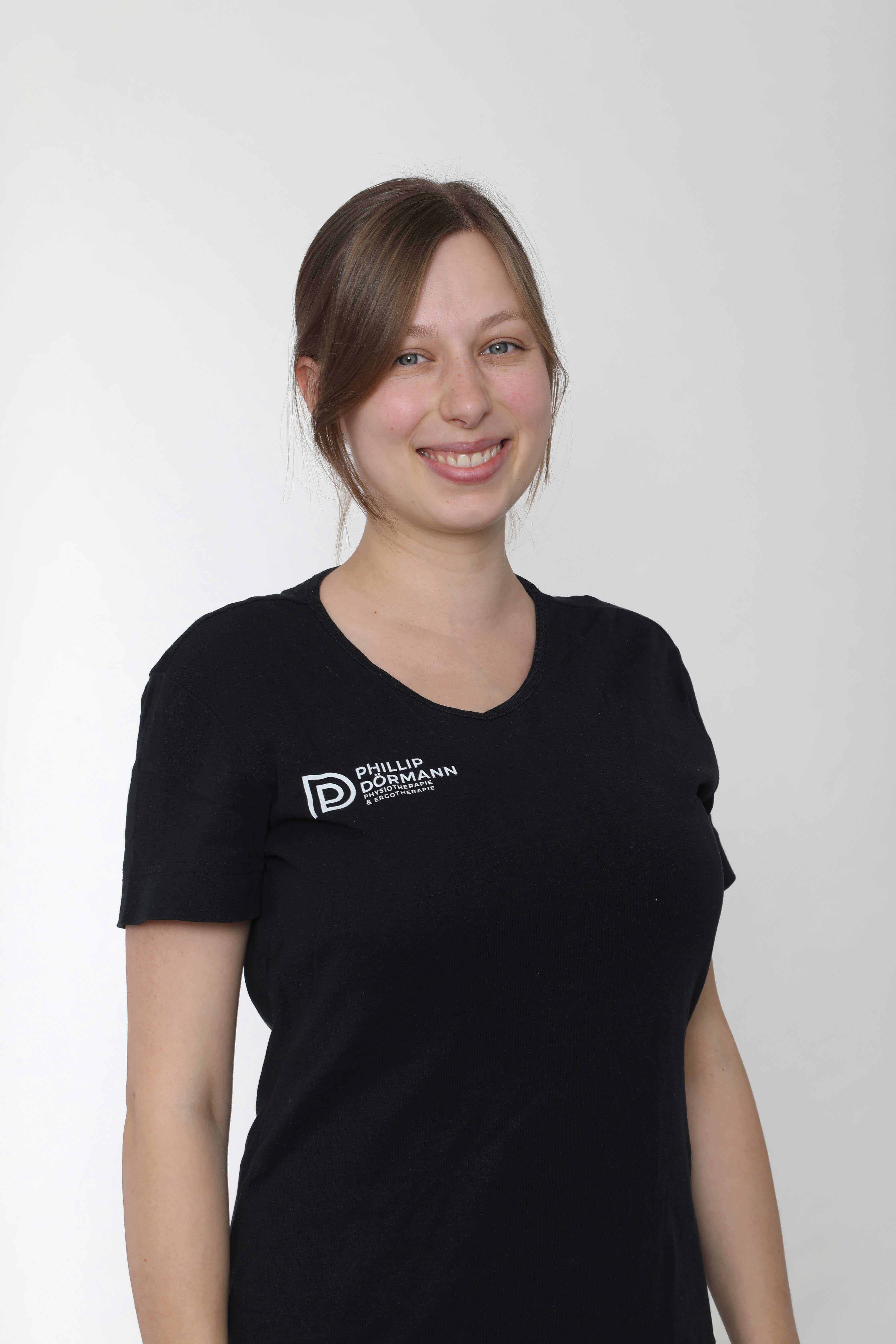 Eine lächelnde Frau mit braunem Haar in einem schwarzen T-Shirt.