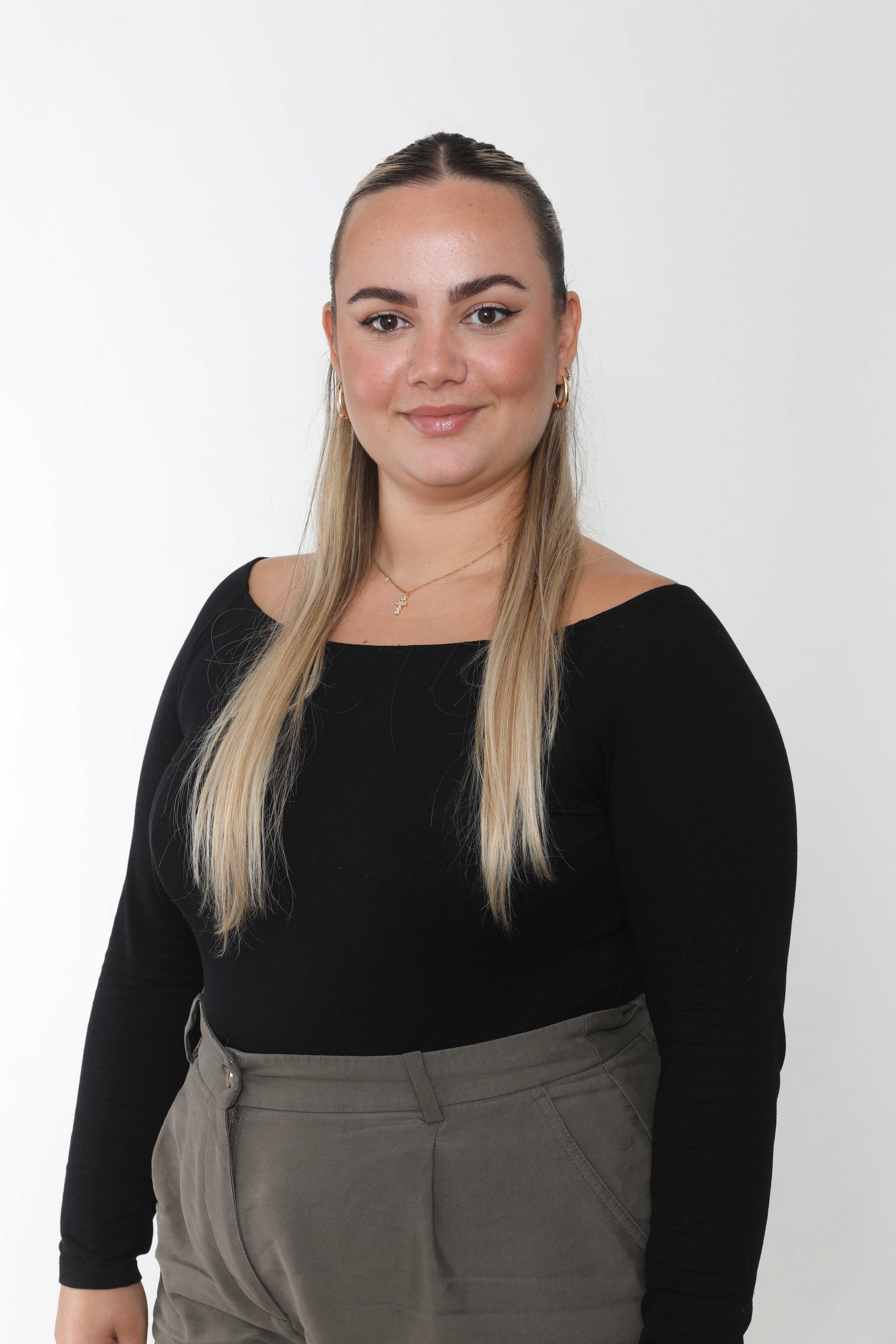Frau mit langem, glattem Haar, trägt schwarzen Pullover, lächelt freundlich.